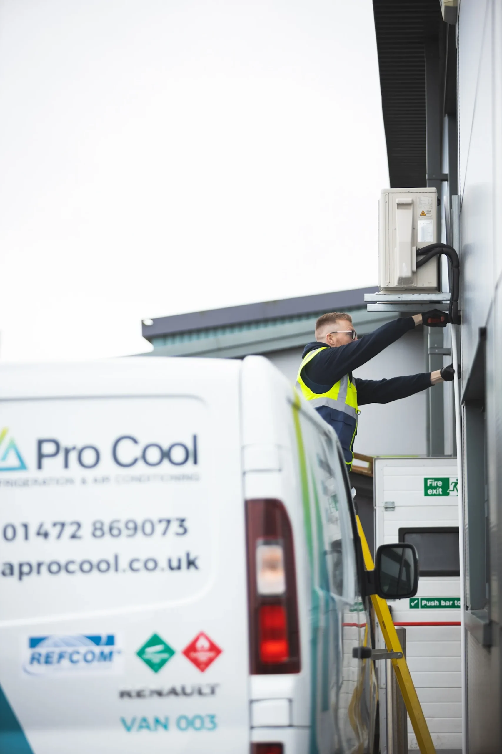 LA Pro Cool engineer servicing a Fujitsu air conditioning unit (side view) with vehicle branding