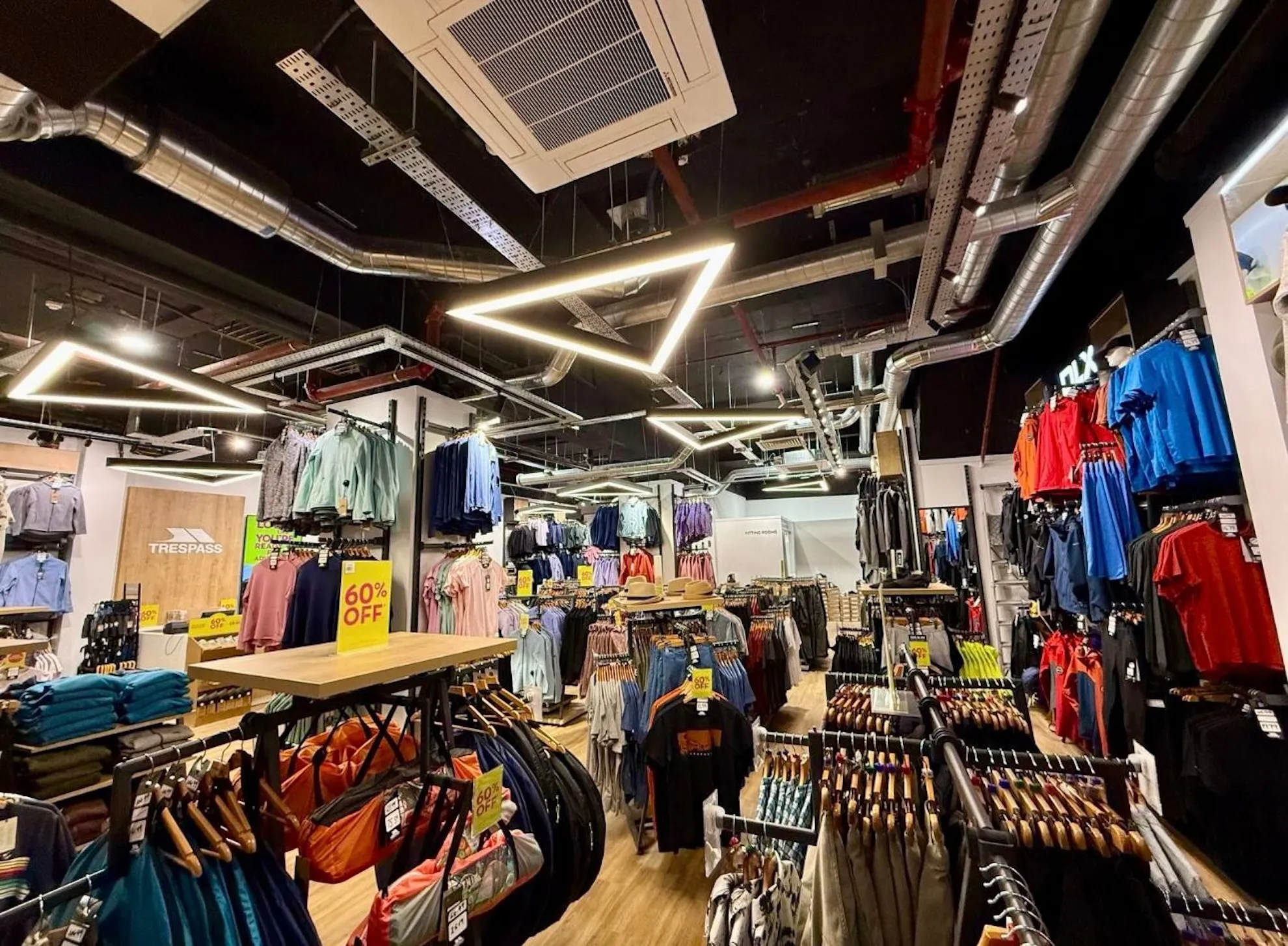 Interior view of a clothing store featuring a variety of apparel on racks, with an air conditioning unit visible on the ceiling, showcasing LA Pro Cool's efficient climate control solutions for retail environments.
